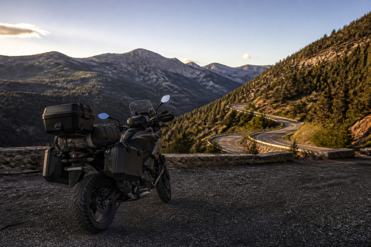 Tourenmotorrad mit Gepäck und Seitenkoffern vor einer kurvigen Straße