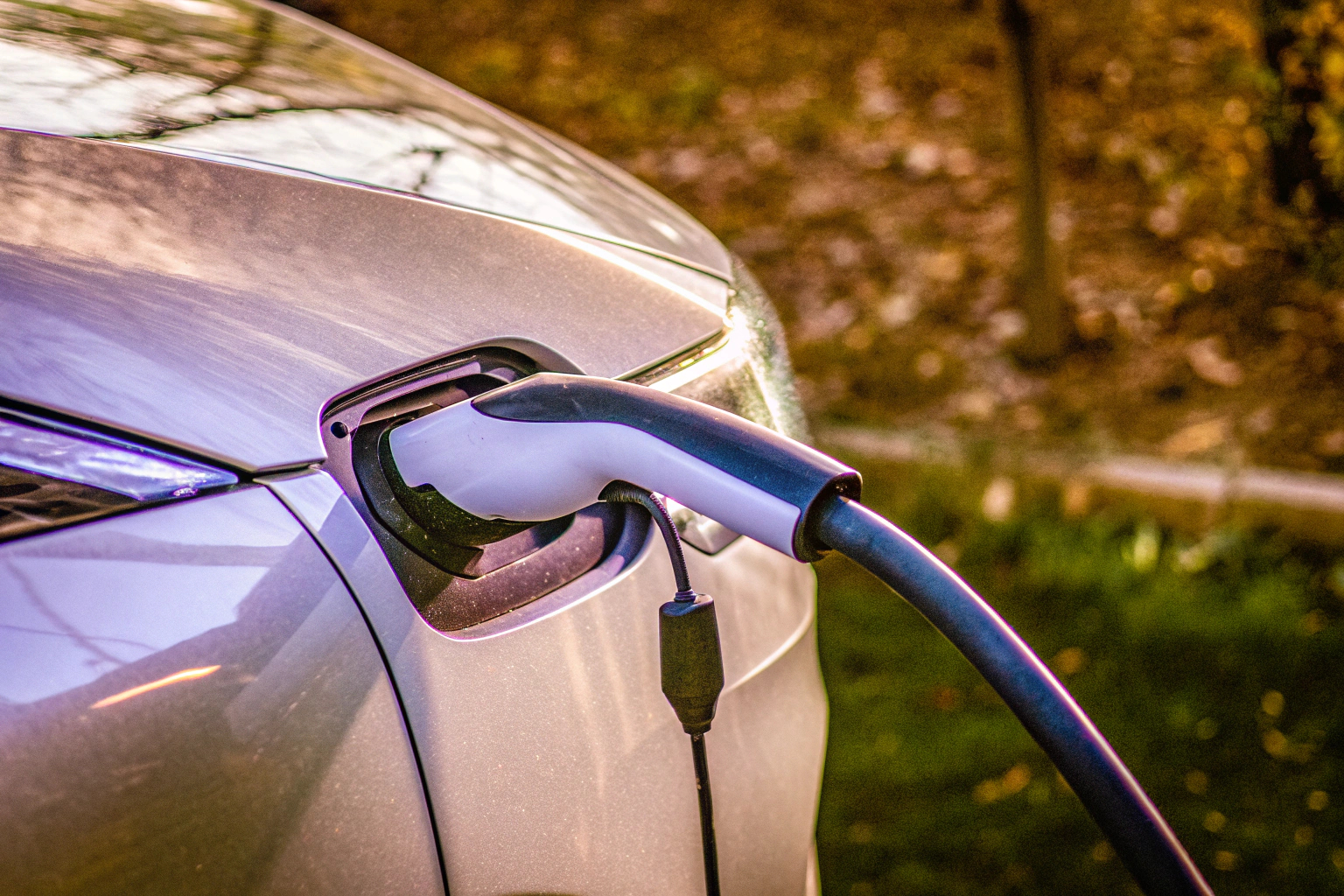 Detailaufnahme eines modernen Elektroautos, das an einer Ladestation angeschlossen ist. Elektroauto an Ladestation