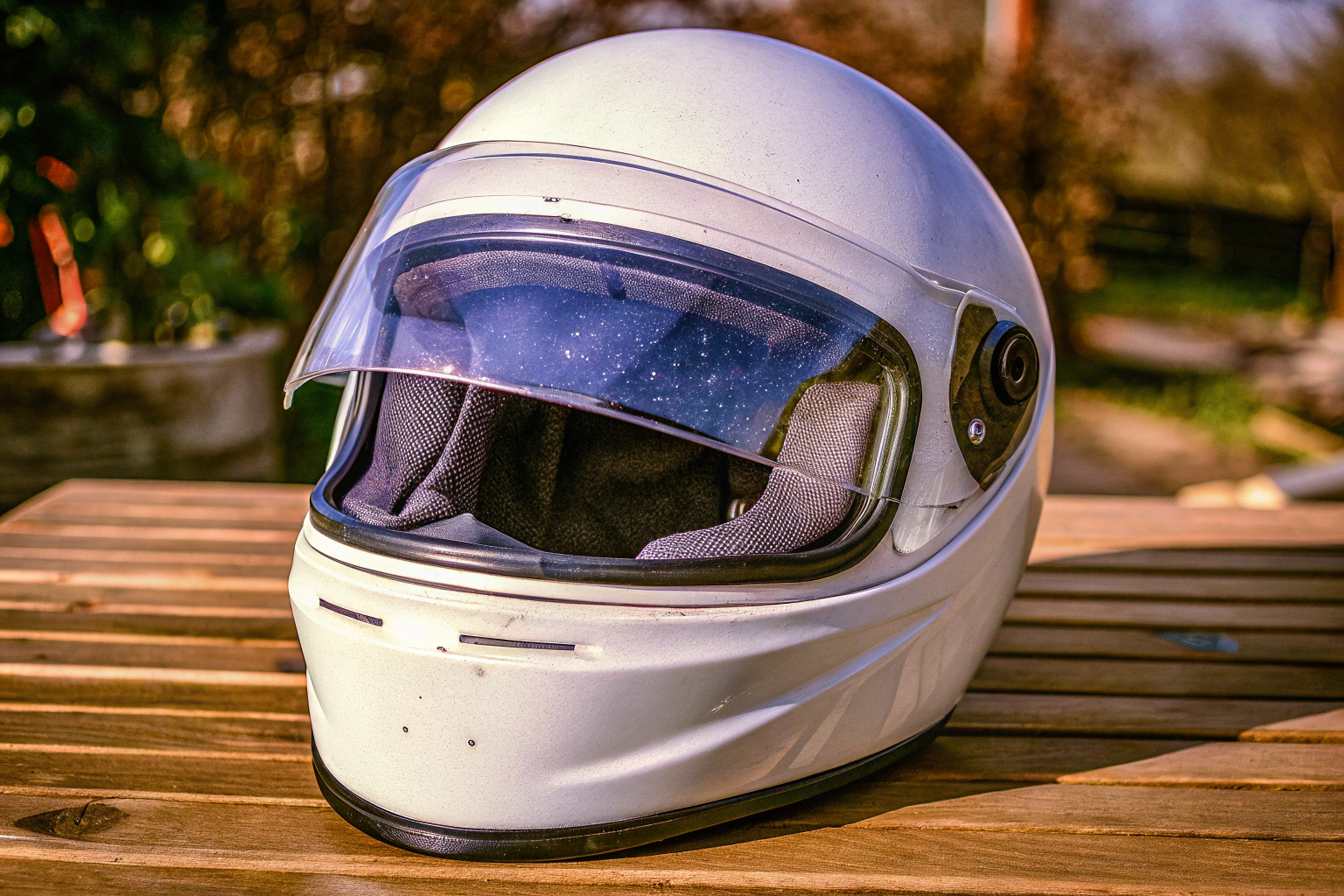 Detailaufnahme eines Motorradhelms, der auf einem Tisch liegt, mit besonderem Fokus auf das Visier und die Belüftungsschlitze. Motorradhelm mit klarem Visier und Belüftungsschlitzen