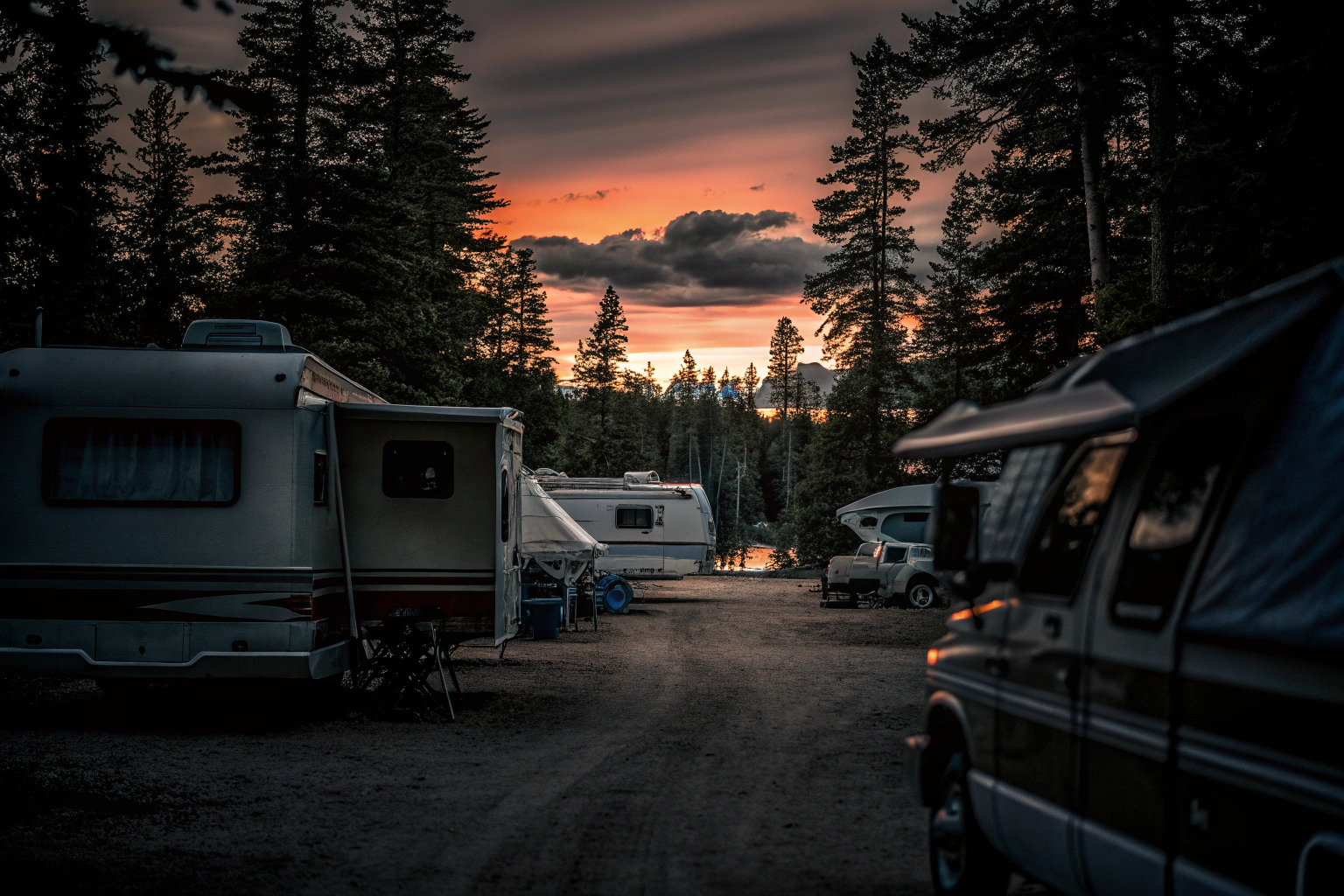 Ein Campingplatz bei Sonnenuntergang mit verschiedenen Wohnmobilen und Zelten. Campingplatz Sonnenuntergang
