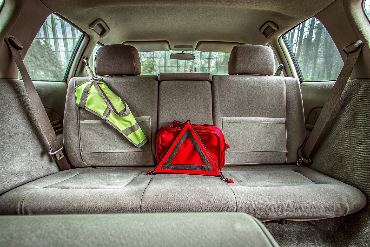 Ein Erste-Hilfe-Set mit Warndreieck und Warnweste im Auto. Erste-Hilfe-Set im Auto