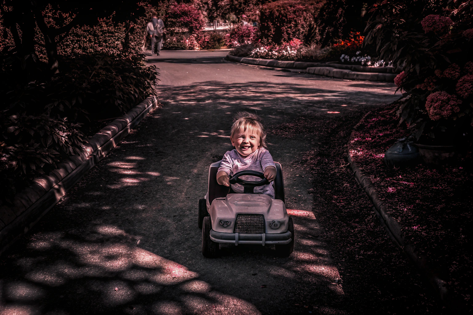 Ein glückliches Kind beim Fahren eines Kinder-Elektroautos im Garten. Kind im Elektroauto