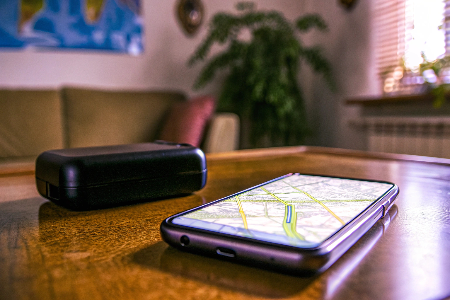 Ein GPS-Tracker, der auf einem Tisch liegt, neben einem Smartphone. GPS-Tracker neben Smartphone
