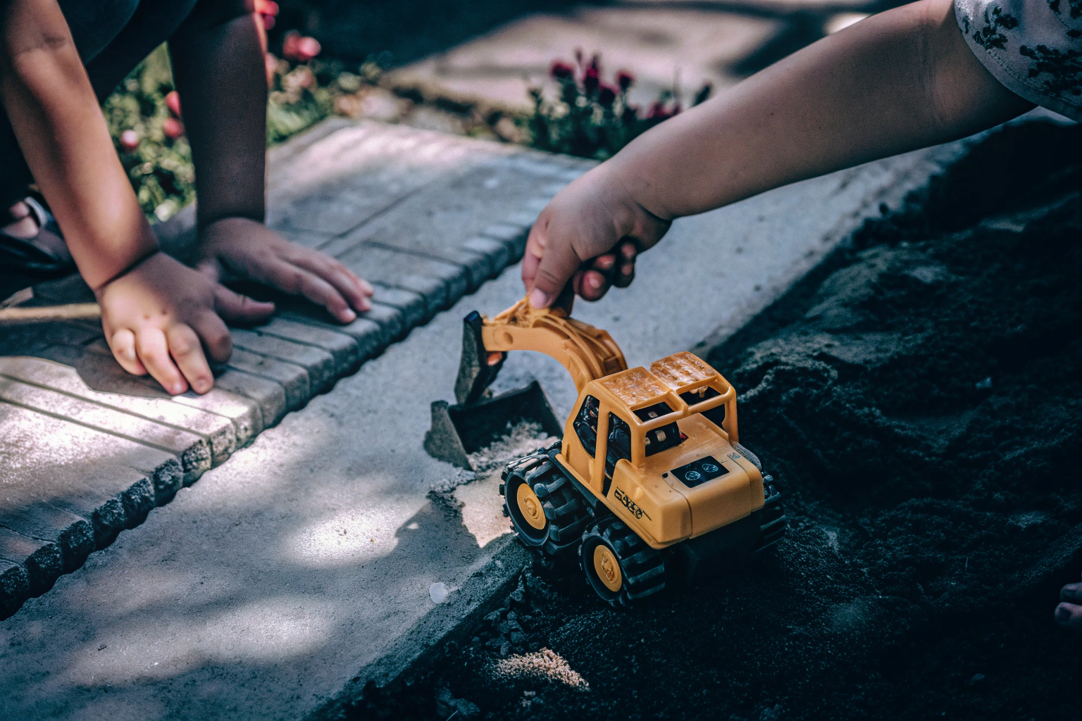 Ein Kind spielt mit einem ferngesteuerten Bagger-Spielzeug im Garten Kind mit Bagger-Spielzeug