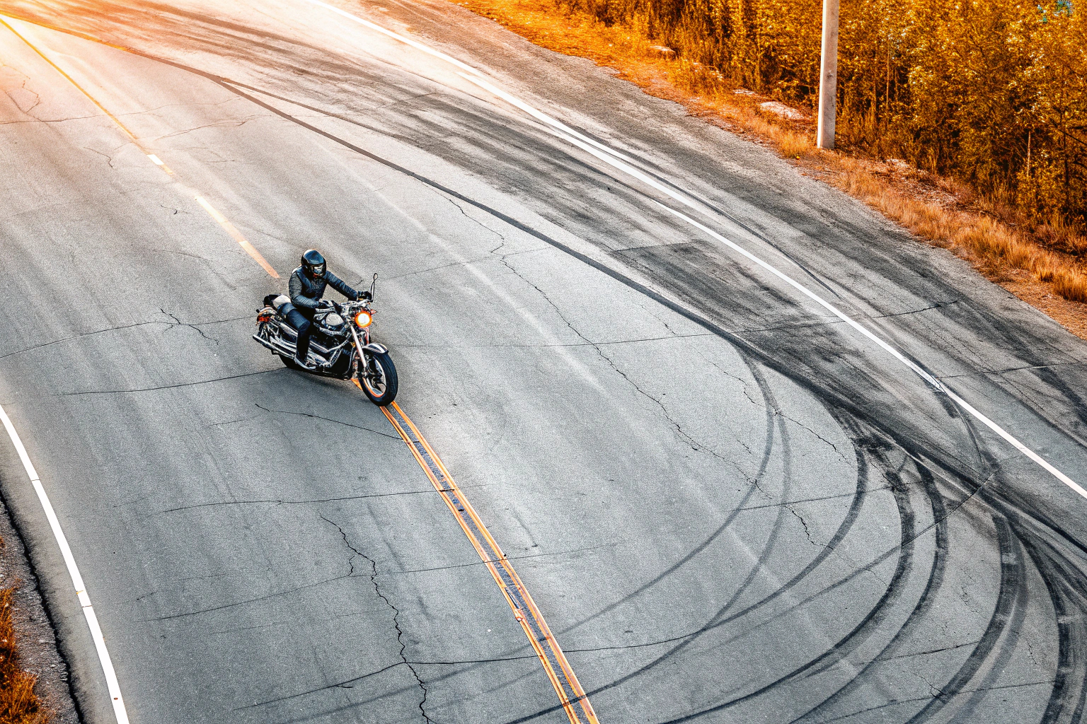 Ein Motorradfahrer auf einer kurvenreichen Landstraße, der die perfekte Kurventechnik demonstriert. Motorradfahrer in Kurve