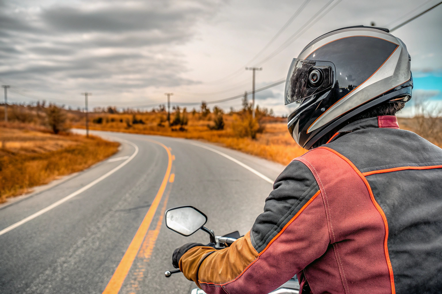 Ein Motorradfahrer auf einer kurvigen Straße, der die SHIMA OpenAir Motorradjacke trägt. Motorradfahrer mit SHIMA OpenAir Motorradjacke auf der Straße