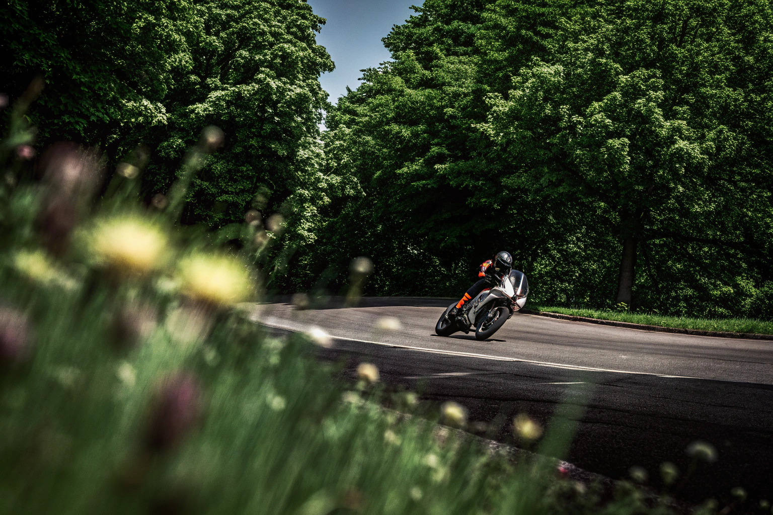 Ein Motorradfahrer, der eine Kurve nimmt und dabei die richtige Körperhaltung beibehält, um die Kurve sicher zu durchfahren. Motorradfahrer in Kurvenlage