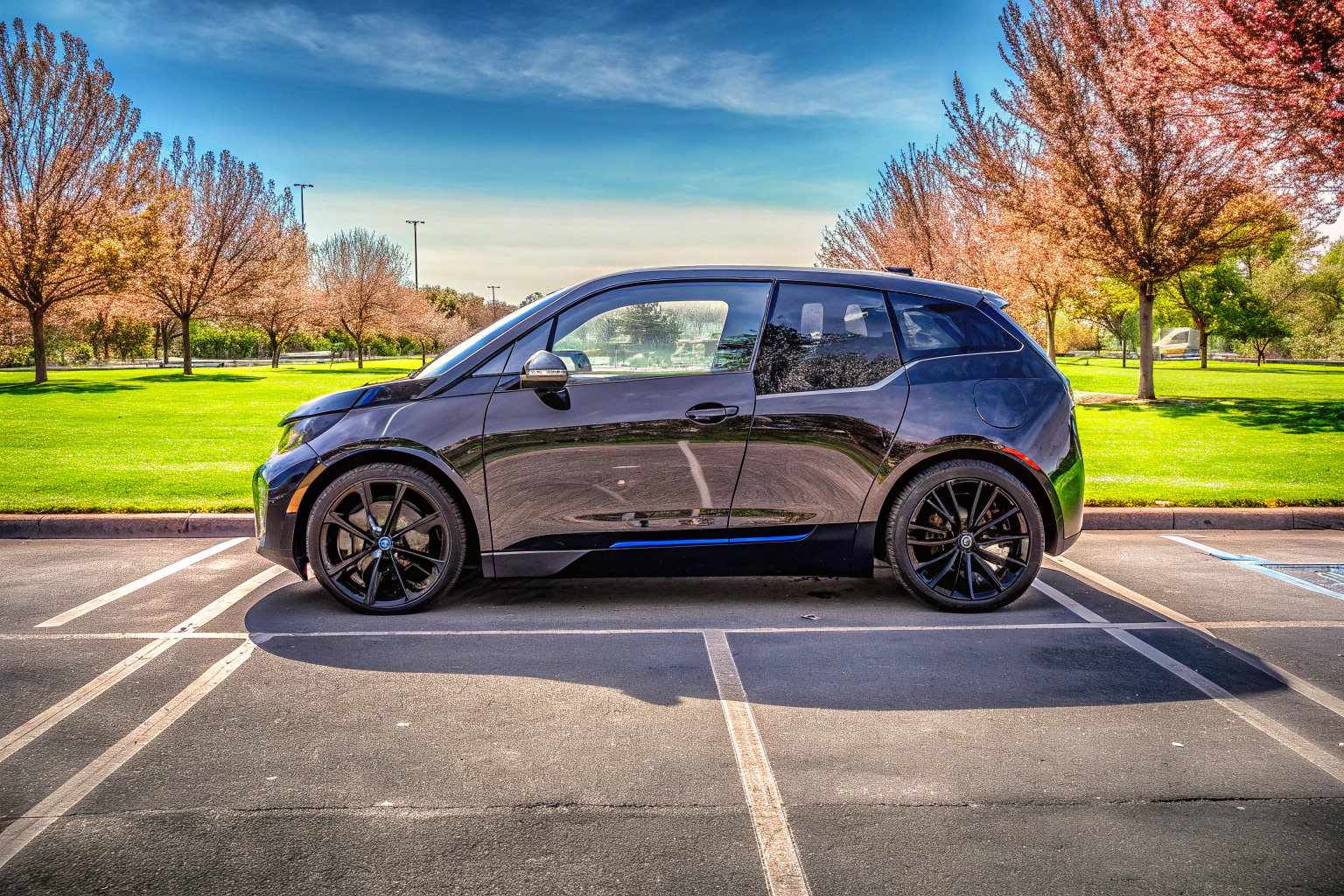 Ein stilvoller BMW i3 auf einem Parkplatz, umgeben von Grünflächen. BMW i3 Elektroauto