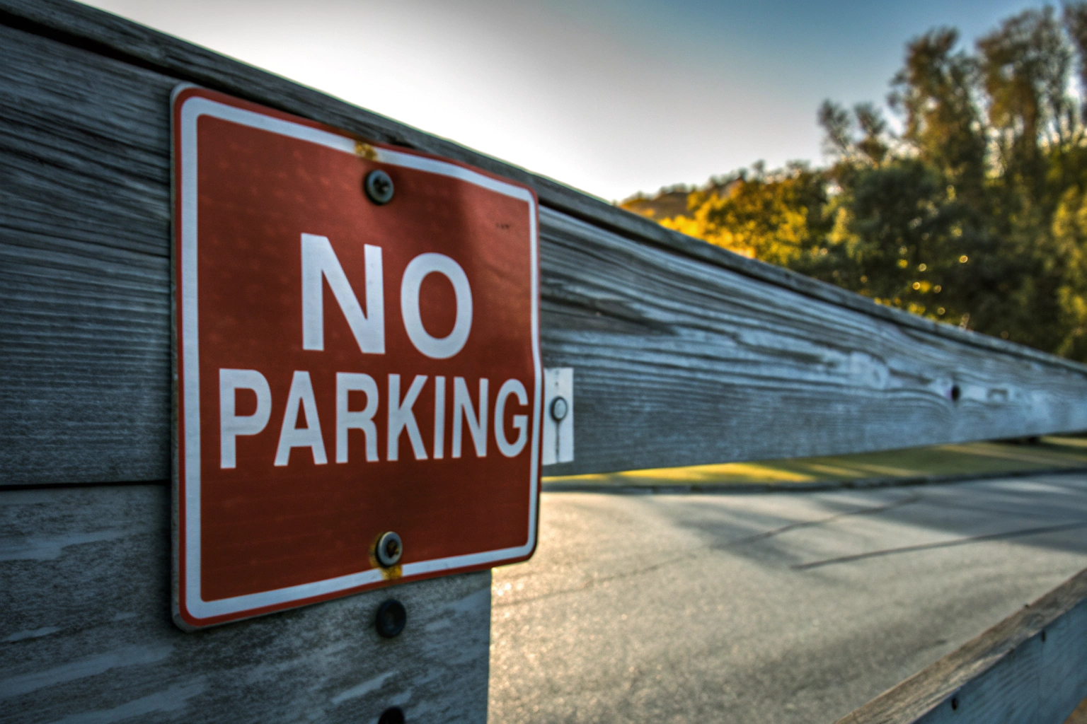 Ein Warnschild, das an einem Zaun befestigt ist, um zu verhindern, dass Fahrzeuge widerrechtlich parken. Warnschild Parken verboten am Zaun
