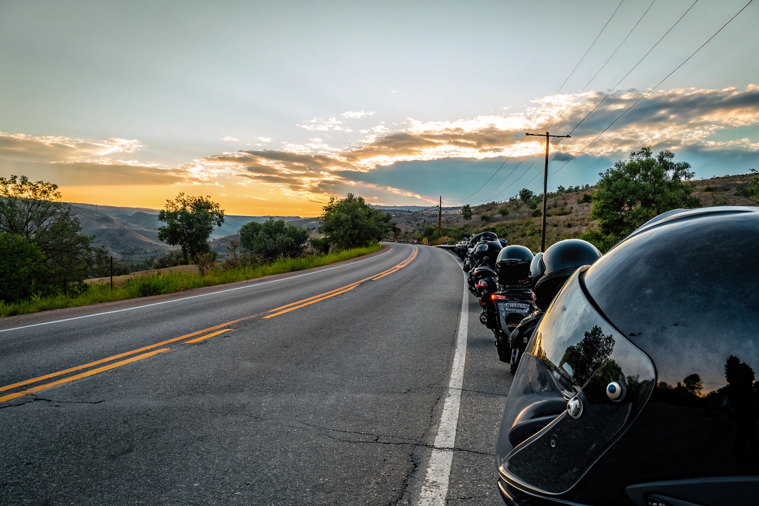 Eine Gruppe von Motorradfahrern auf einer Landstraße bei Sonnenuntergang. Motorradfahrer auf der Landstraße