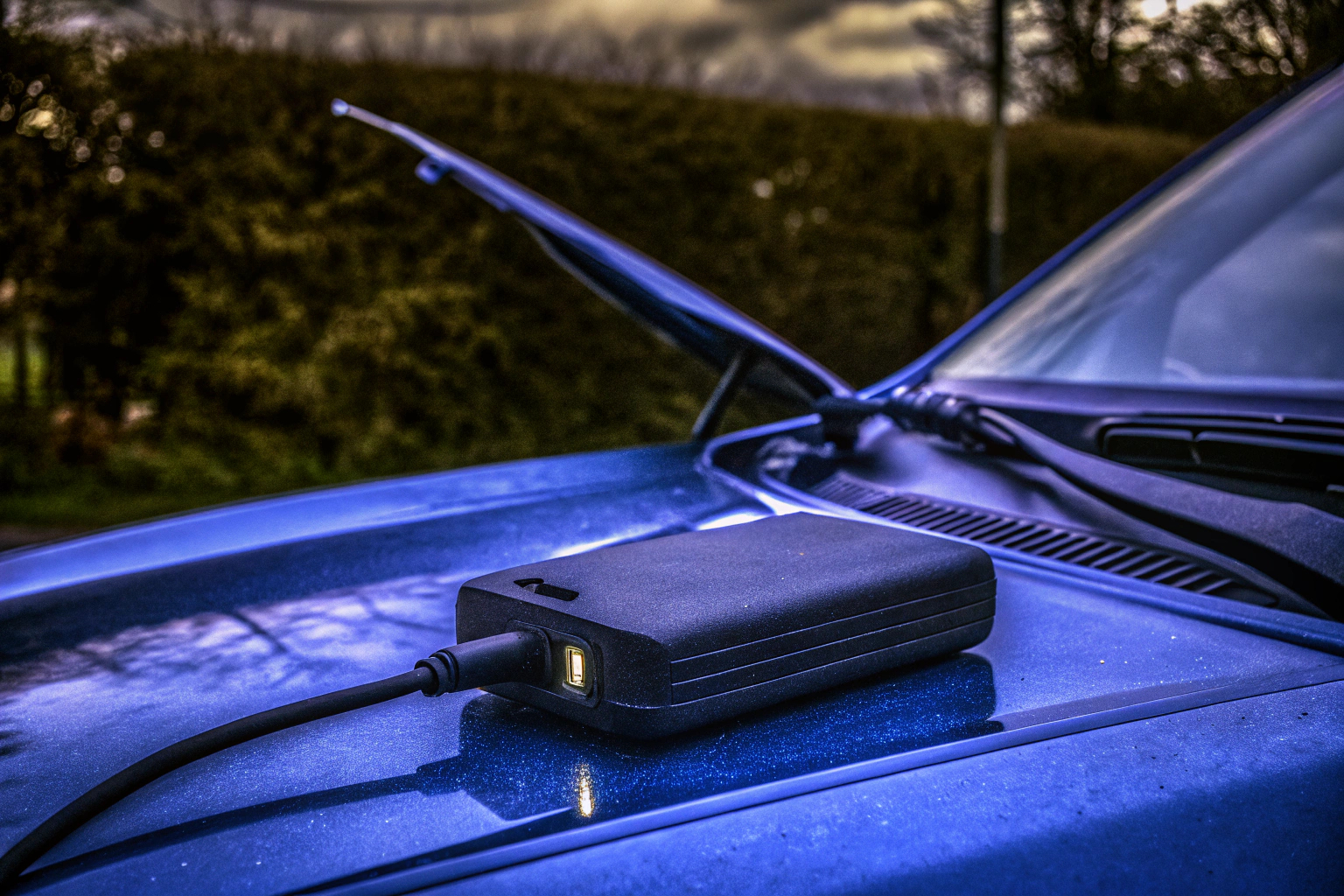 Eine Person verwendet eine Starthilfe-Powerbank, um ein Auto zu starten. Starthilfe-Powerbank im Einsatz