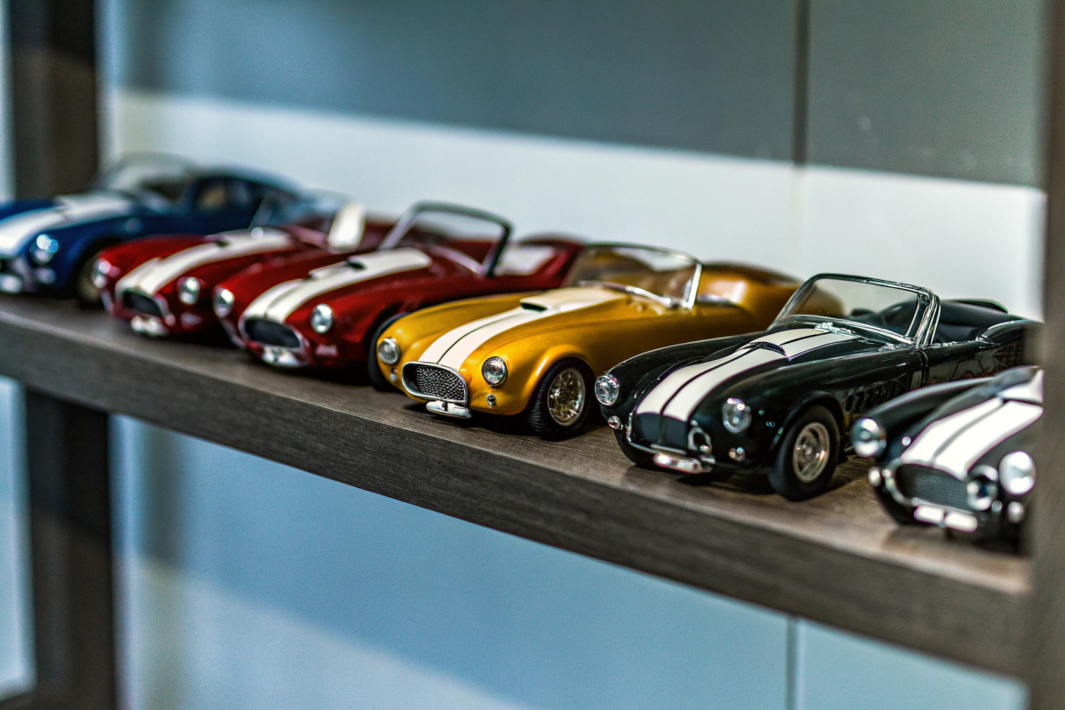 Eine Sammlung von Miniatur-Sportwagenmodellen auf einem Regal. Miniatur-Sportwagenmodelle